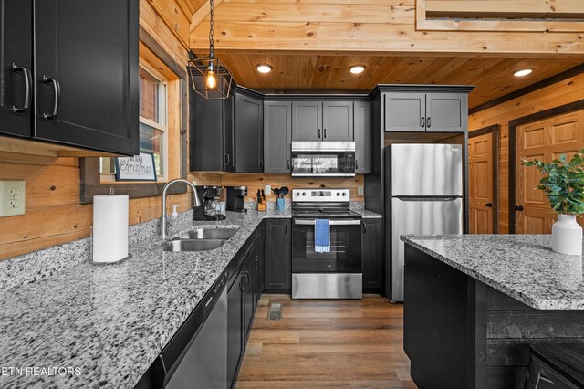 kitchen featuring light stone countertops, recessed lighting, dark cabinets, a sink, and appliances with stainless steel finishes