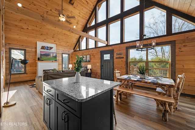 kitchen featuring wood walls, a kitchen island, high vaulted ceiling, dark cabinetry, and light wood-style flooring