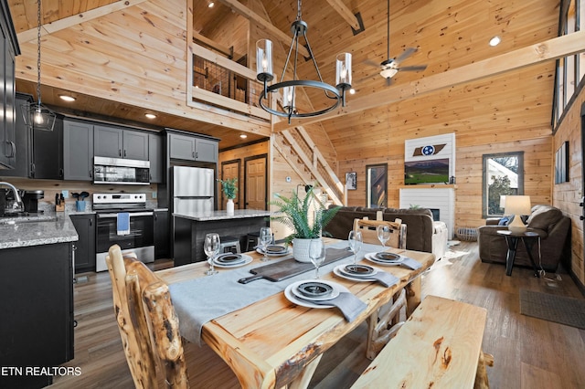 dining area with wood walls, beam ceiling, wood finished floors, wooden ceiling, and high vaulted ceiling