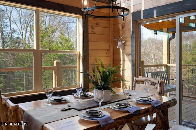 dining room featuring wood walls and a notable chandelier