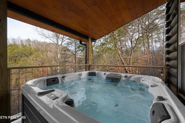 deck with a hot tub and a forest view