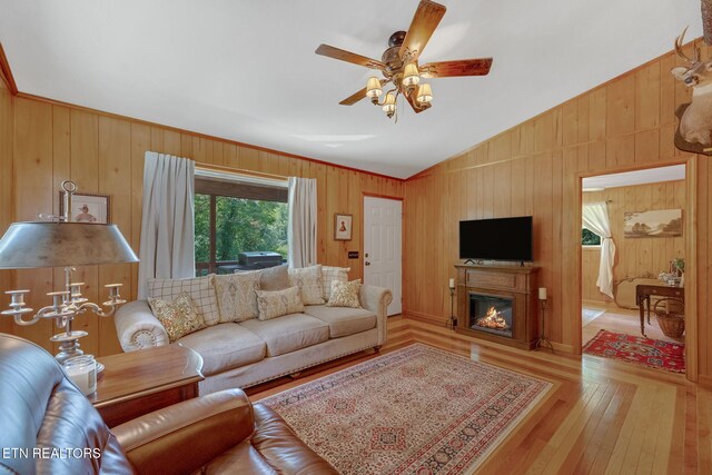 3009 Winding Way, Cosby, TN 37722 - living room with vaulted ceiling, light wood-type flooring, a ceiling fan, a glass covered fireplace, and wooden walls