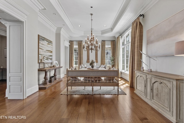 dining room with a raised ceiling, a chandelier, baseboards, wood finished floors, and ornamental molding