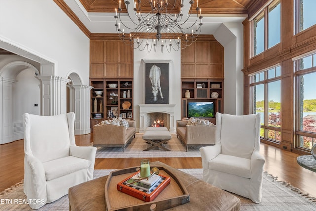 living area featuring a high ceiling, an inviting chandelier, built in shelves, and wood finished floors