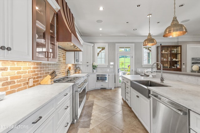 kitchen featuring crown molding, a sink, appliances with stainless steel finishes, and glass insert cabinets