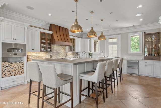 kitchen featuring crown molding, a kitchen breakfast bar, white cabinetry, custom range hood, and a kitchen island
