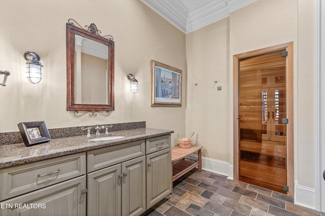 bathroom featuring baseboards, ornamental molding, vanity, and stone finish flooring