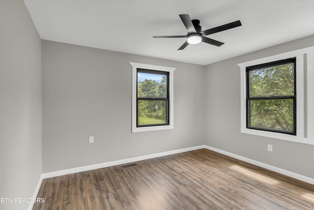 unfurnished room with baseboards, ceiling fan, wood finished floors, and visible vents