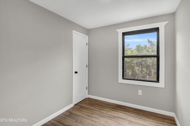 spare room featuring baseboards and wood finished floors