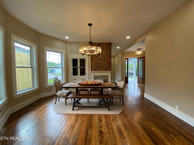 dining room featuring dark wood-style flooring, baseboards, an inviting chandelier, and a healthy amount of sunlight
