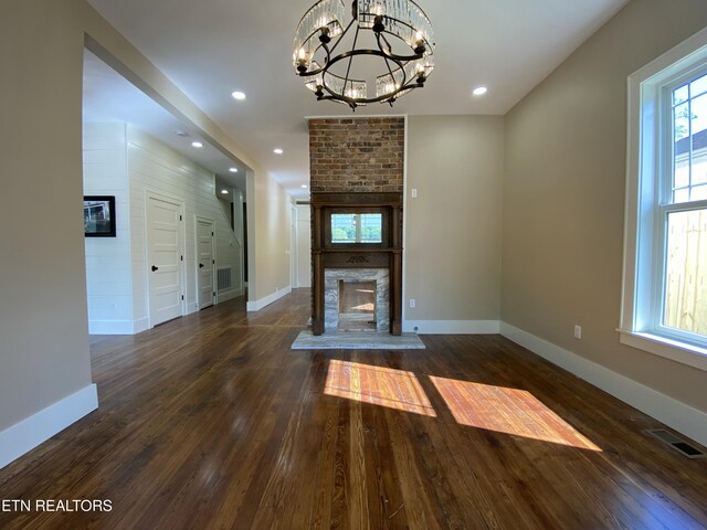 unfurnished living room with wood-type flooring, baseboards, visible vents, and a fireplace