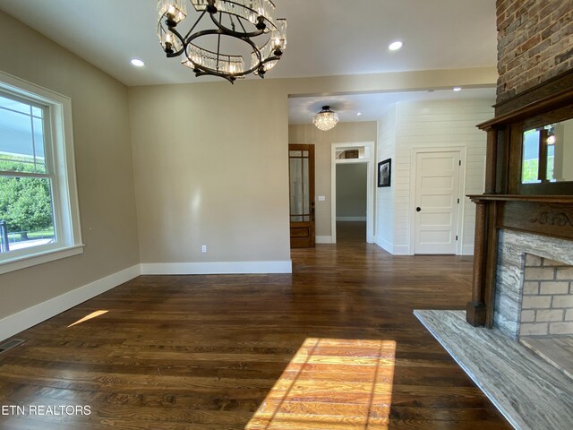 unfurnished living room featuring recessed lighting, baseboards, an inviting chandelier, and wood finished floors