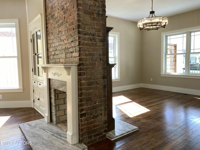 unfurnished living room featuring a healthy amount of sunlight, baseboards, and dark wood finished floors