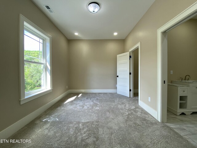unfurnished bedroom with baseboards, light colored carpet, and visible vents