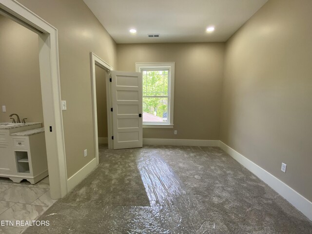 unfurnished room featuring light colored carpet, a sink, recessed lighting, baseboards, and visible vents