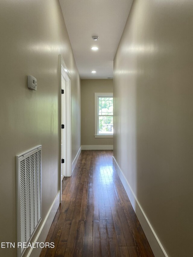 hallway featuring baseboards, dark wood-type flooring, and visible vents