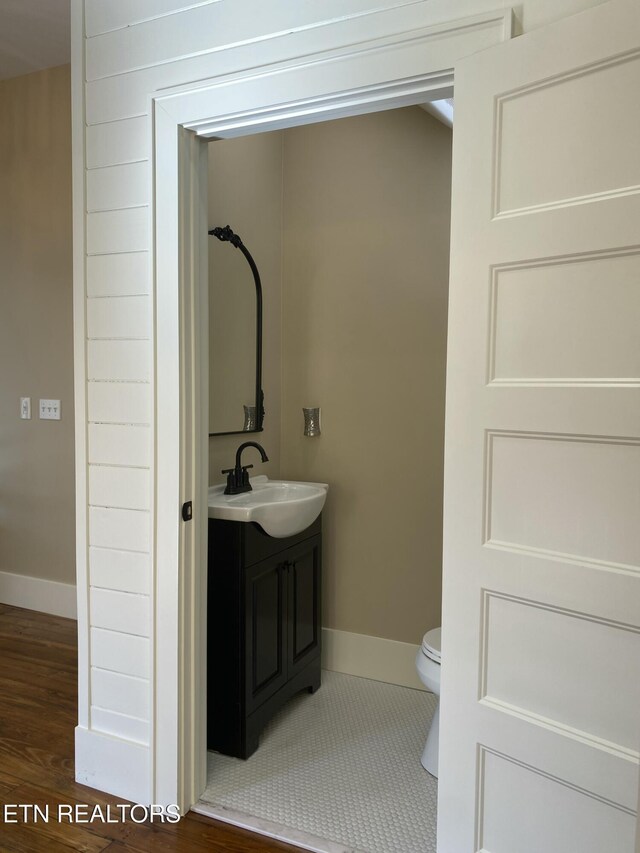 bathroom with toilet, baseboards, wood finished floors, and vanity