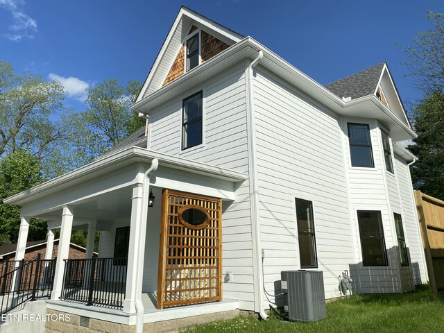 back of property with a shingled roof, central AC, and covered porch