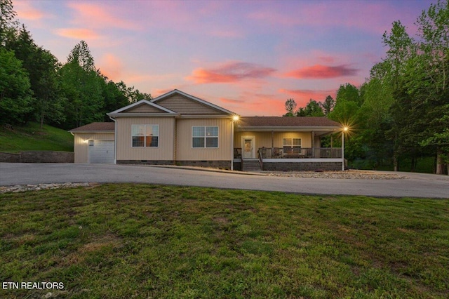 single story home featuring a porch, a garage, a front yard, and aphalt driveway