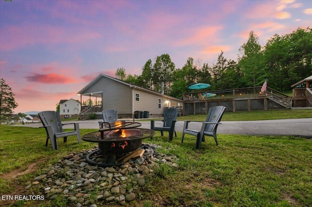 back of house at dusk featuring stairway, an outdoor fire pit, a yard, and a deck