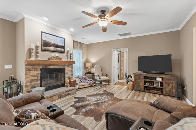 living room featuring visible vents, ornamental molding, wood finished floors, a fireplace, and a ceiling fan