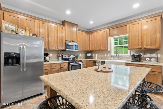 kitchen featuring a kitchen island, a sink, a breakfast bar, stainless steel appliances, and recessed lighting