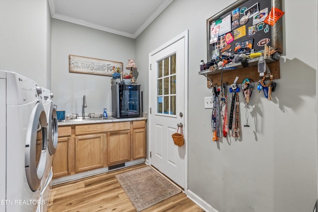 clothes washing area featuring washer and dryer, cabinet space, a sink, light wood finished floors, and ornamental molding