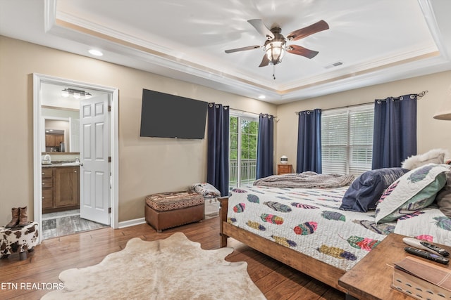 bedroom featuring a tray ceiling, wood finished floors, and visible vents