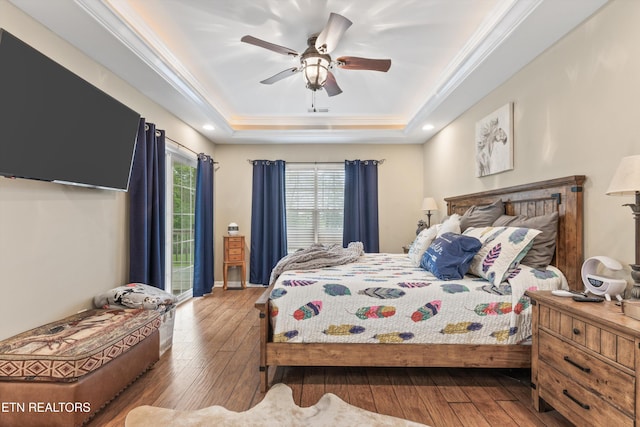 bedroom featuring crown molding, ceiling fan, a raised ceiling, baseboards, and hardwood / wood-style flooring