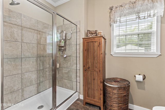 bathroom with crown molding, baseboards, wood finished floors, and a shower stall