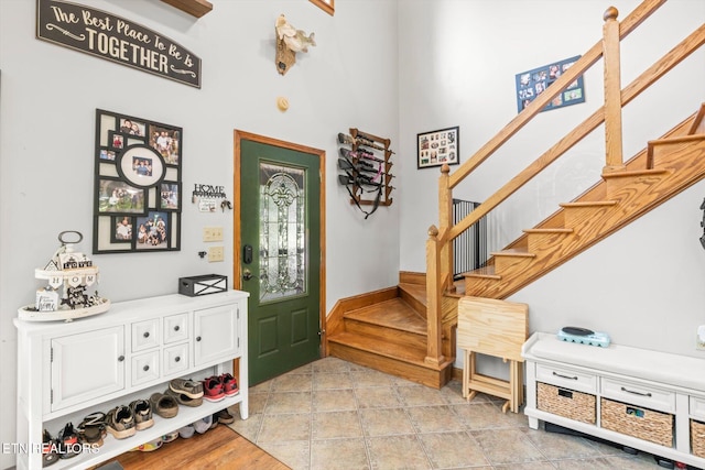 entryway featuring stairs, a towering ceiling, and light tile patterned flooring