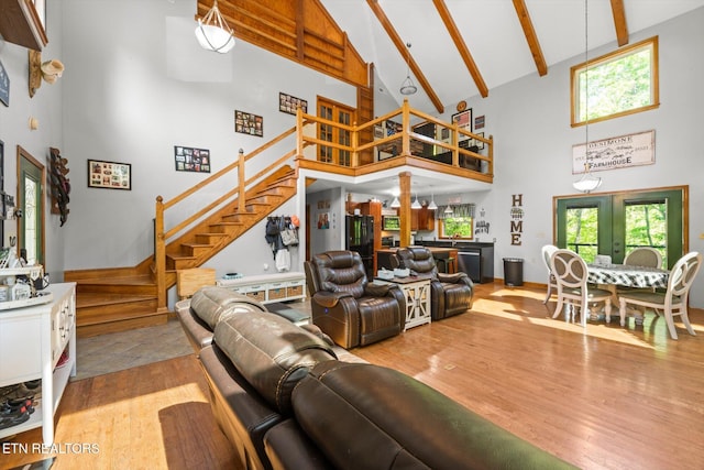 living room with stairs, wood finished floors, high vaulted ceiling, and beamed ceiling