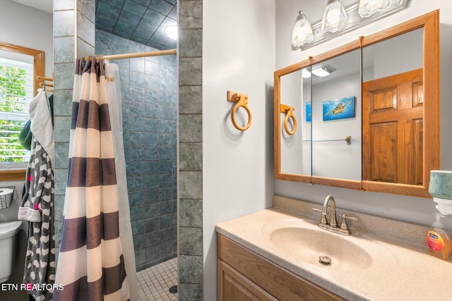 full bath featuring vanity, a tile shower, and toilet