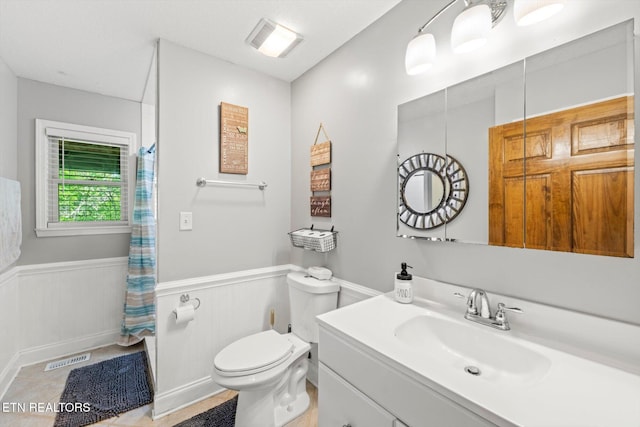 bathroom with a wainscoted wall, toilet, and curtained shower