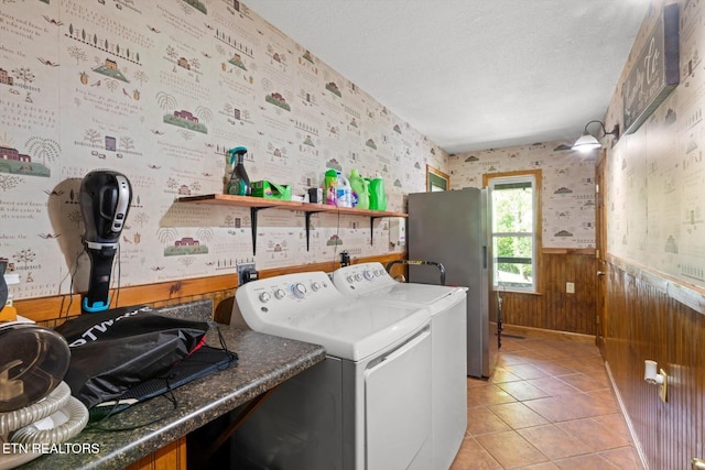 washroom featuring laundry area, a textured ceiling, wainscoting, washing machine and dryer, and wallpapered walls