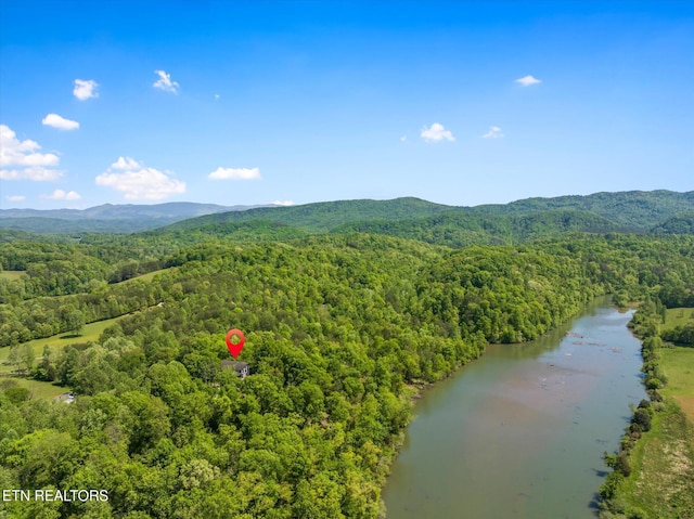 drone / aerial view featuring a water and mountain view and a wooded view