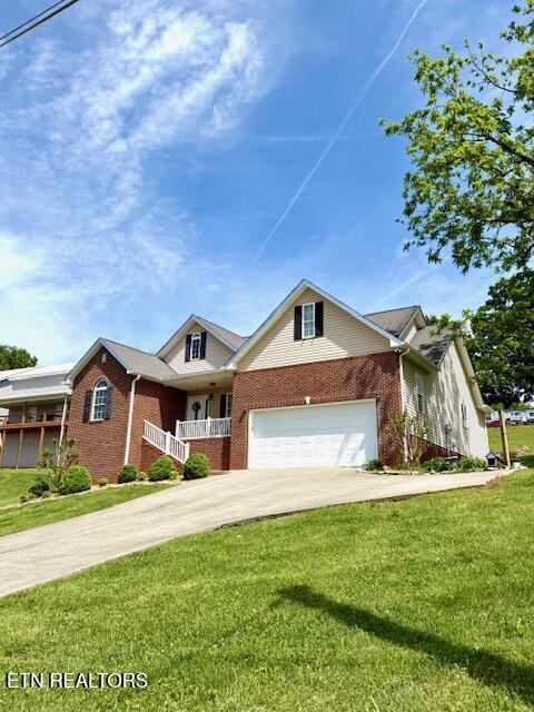 217 Loomis St, Tellico Plains, TN 37385 - view of front of home featuring covered porch, a front yard, a garage, brick siding, and concrete driveway