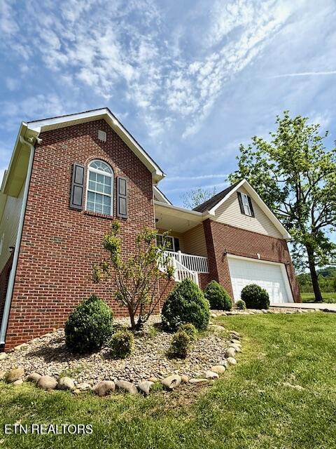 217 Loomis St, Tellico Plains, TN 37385 - view of front of house featuring an attached garage, a front lawn, and brick siding