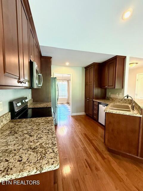 217 Loomis St, Tellico Plains, TN 37385 - kitchen featuring wood finished floors, recessed lighting, light stone counters, a sink, and appliances with stainless steel finishes