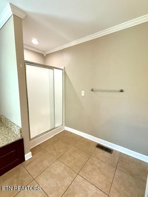 217 Loomis St, Tellico Plains, TN 37385 - bathroom featuring crown molding, tile patterned flooring, baseboards, visible vents, and a stall shower