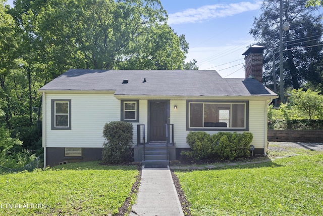 view of front of house with a chimney and a front lawn