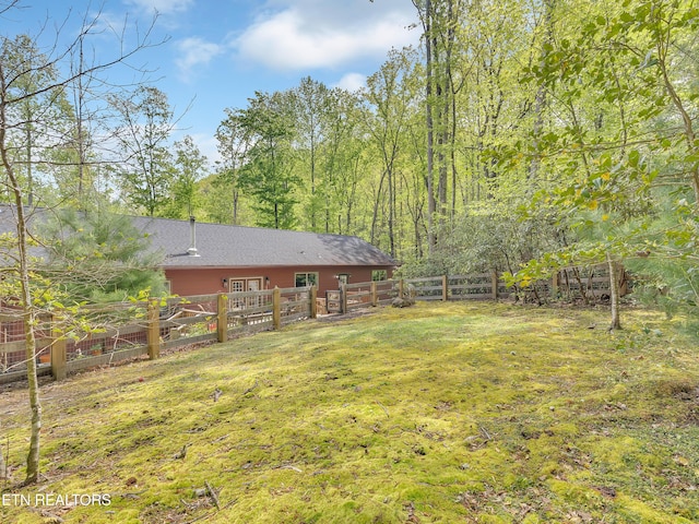 view of yard with a fenced backyard and a view of trees