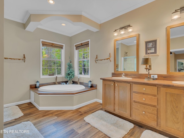 full bathroom with a bath, ornamental molding, and wood finished floors
