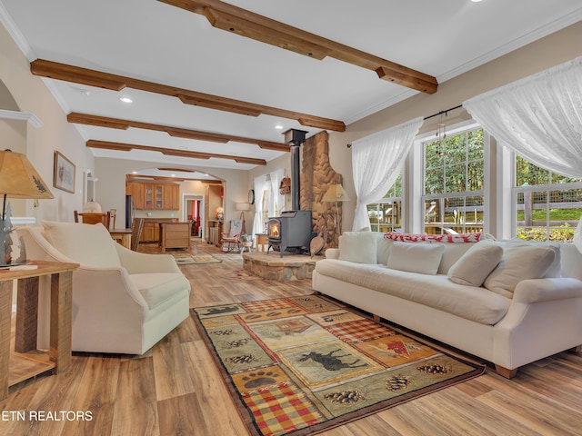 living area featuring arched walkways, beamed ceiling, a wood stove, and light wood-style flooring