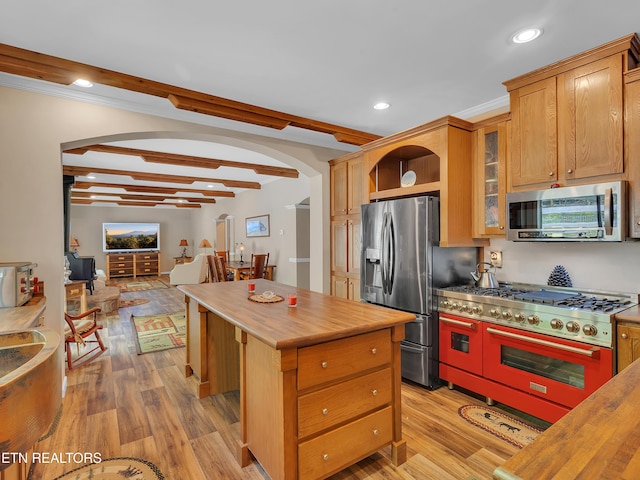 kitchen with appliances with stainless steel finishes, arched walkways, wood counters, light wood-type flooring, and beamed ceiling