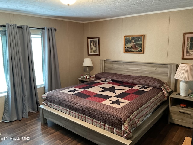 bedroom featuring a textured ceiling, ornamental molding, wood finished floors, and a decorative wall