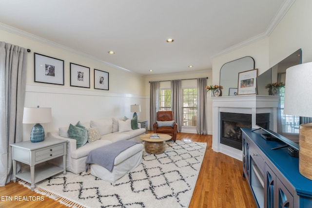 living room with crown molding, a fireplace, recessed lighting, and wood finished floors