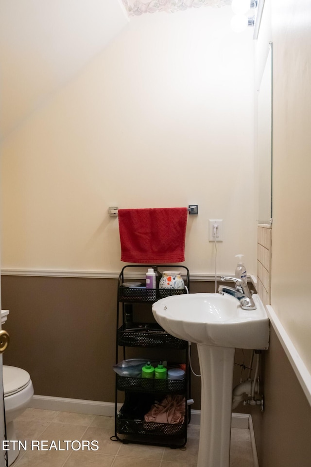 half bathroom featuring tile patterned flooring, baseboards, and toilet