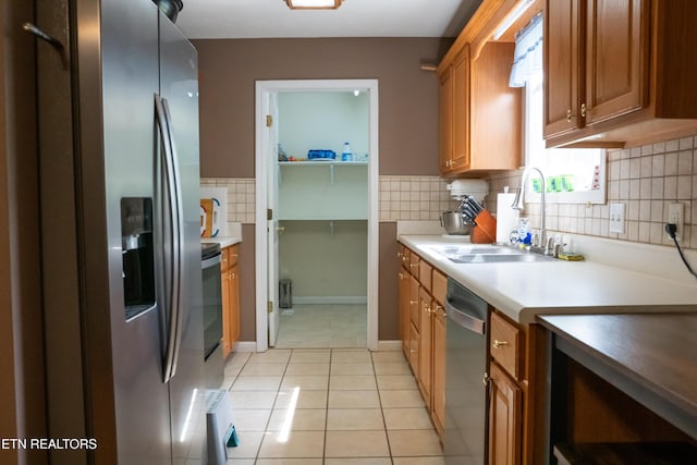kitchen featuring light tile patterned floors, appliances with stainless steel finishes, decorative backsplash, and a sink