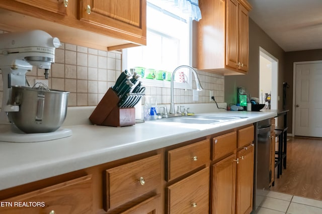 kitchen with a sink, decorative backsplash, brown cabinets, and light countertops